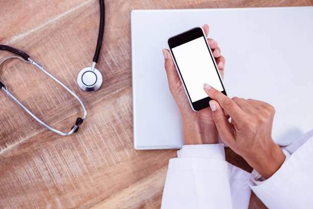 istock Doctor using smartphone on wooden desk 664406770