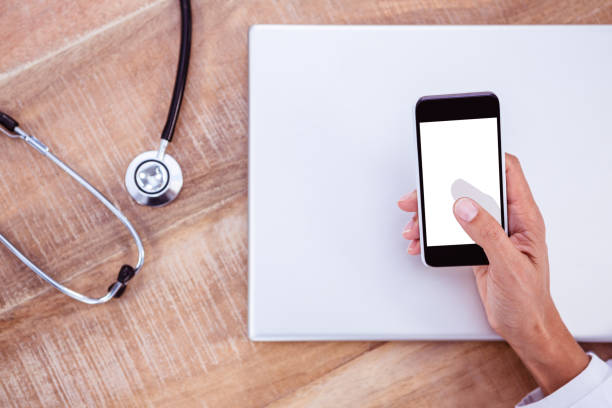 istock Doctor using smartphone on wooden desk 664407284