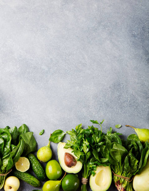 Green vegetables and herbs assortment on a grey stone background. Top view. Copy space