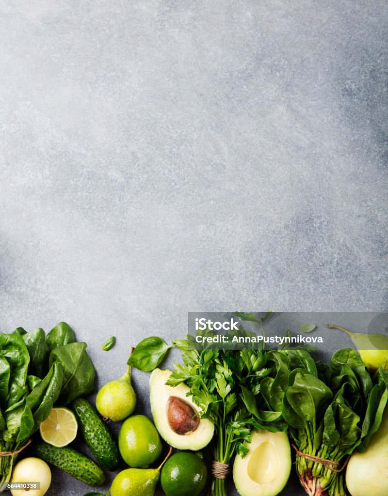 Green vegetables and herbs assortment on a grey stone background. Top view. Copy space Green vegetables and herbs assortment on a grey stone background. Top view. Copy space. Food Stock Photo