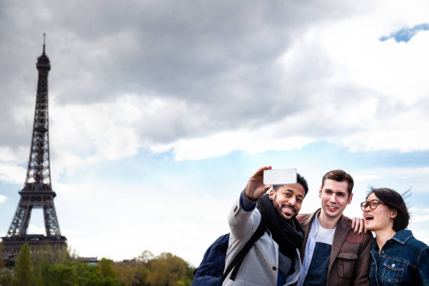 istock three multi-ethnic young friends have fun posing for selfies  in spring sunshine together by Eiffel Tower in Paris 664410550