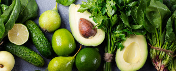 istock Green vegetables and herbs assortment on a grey stone background. Top view. Copy space 664410934