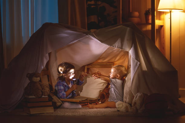 niños niño y niña jugando y asustarse unos a otros en la tienda de campaña - child bedtime imagination dark fotografías e imágenes de stock