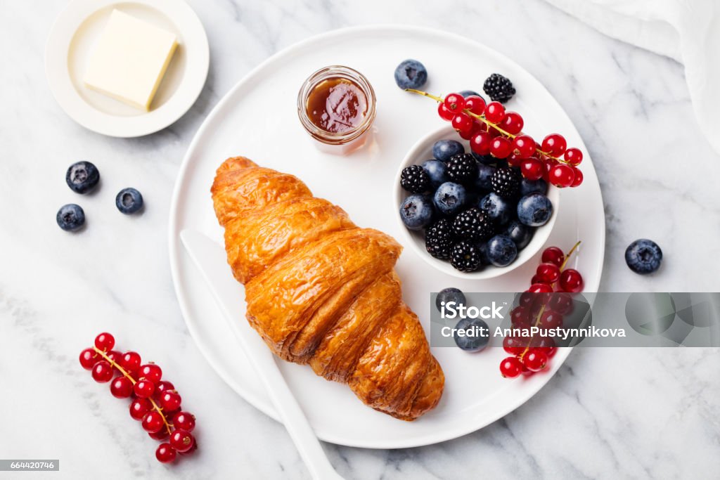 Croissant with fresh berries and butter on a marble texture background. Top view Croissant with fresh berries and butter on a marble texture background. Top view. Croissant Stock Photo