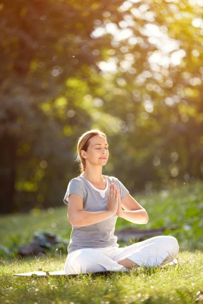 mujer meditando en yoga pose - senior women caucasian one person religion fotografías e imágenes de stock