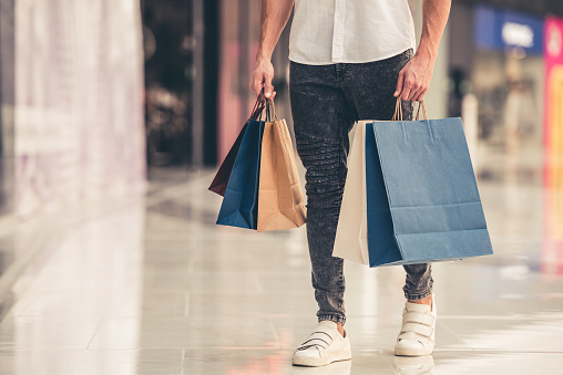 Cropped image of handsome guy with shopping bags doing shopping in the mall