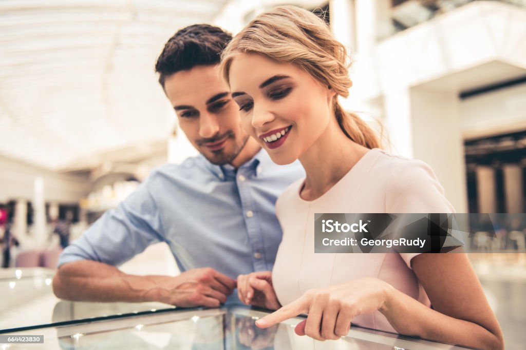 Couple buying jewelry Beautiful couple is smiling while choosing jewelry in the shopping mall Shopping Stock Photo