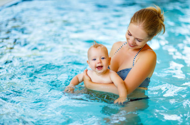 mother and baby swim  in pool - blue water swimming pool sports and fitness imagens e fotografias de stock