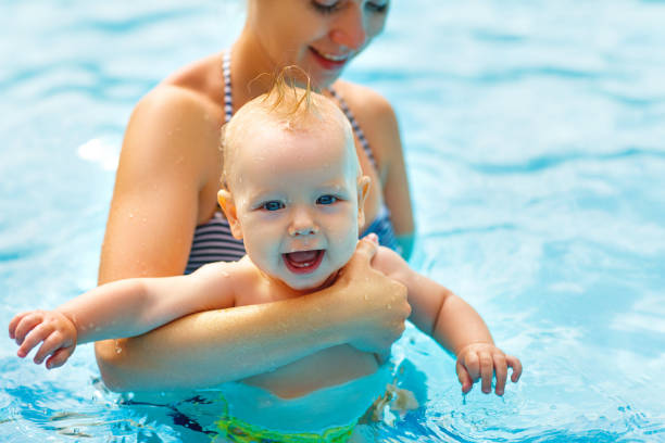 madre y bebé nadan en la piscina - bebe bañandose fotografías e imágenes de stock