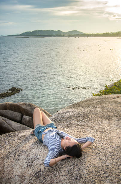istock Girl lying on the cliff above seaside at sunset 664434232