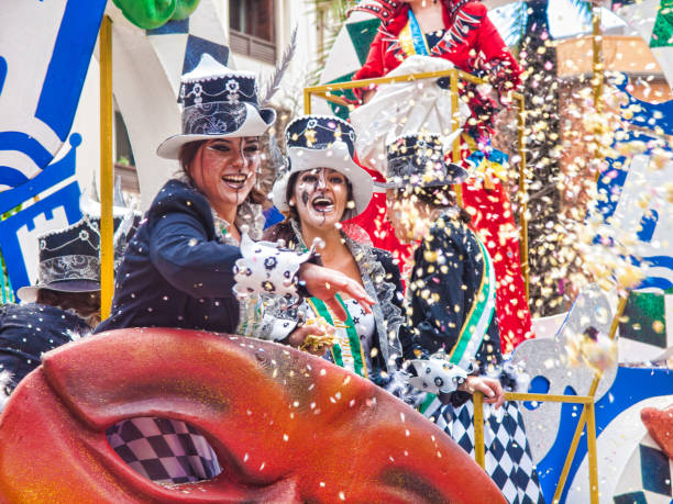 Carnival Algeciras, Cádiz; Spain, 2017. Participants throw confetti Algeciras: Cheerful laughing Carnival participants throw confetti during the parade of the carnival in the street  in Algeciras, Cadiz, Andalusia parade stock pictures, royalty-free photos & images