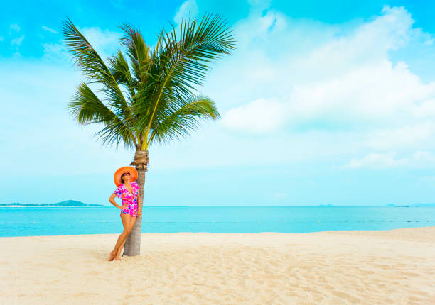 Woman at tropical beach in long dress and sun hatWoman at tropical beach in long dress and sun hat