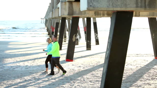 Mature couple exercising, walking on beach
