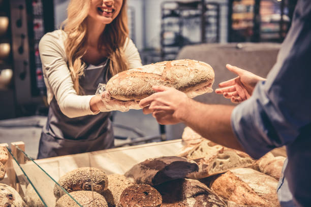 At the supermarket At the supermarket. Cropped image of beautiful young female worker offering a bread to the customer and smiling retail place stock pictures, royalty-free photos & images