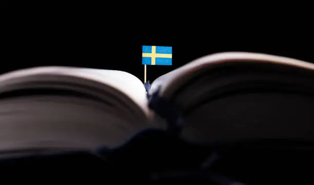 Photo of Swedish flag in the middle of the book. Knowledge and education concept.