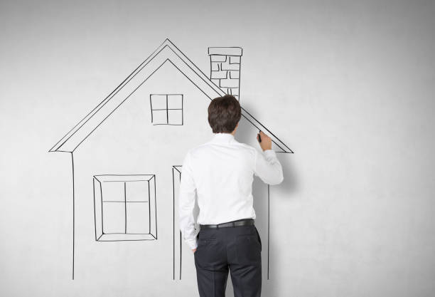 istock Rear view of a man drawing a house on concrete 664450182