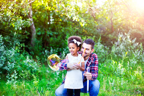 istock Happy father and daughter playing soap bubbles in park. 664451784