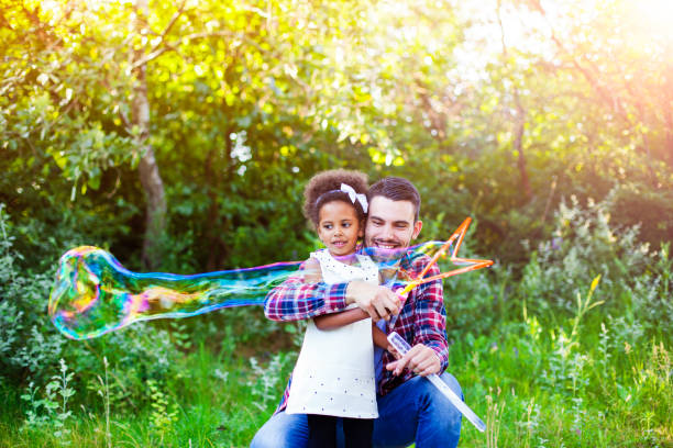 istock Happy father and daughter playing soap bubbles in park. 664454556
