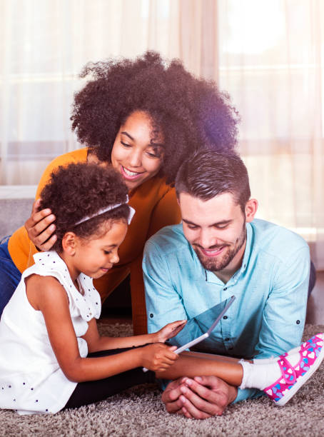 Family lying on carpet and playing games on digital tablet Family lying on carpet and playing games on digital tablet lifestyles teaching little girls child stock pictures, royalty-free photos & images