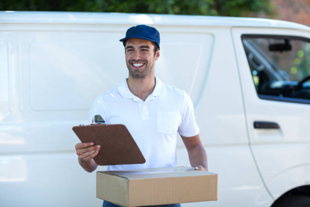 istock Smiling delivery man with clipboard and cardboard box 664465560
