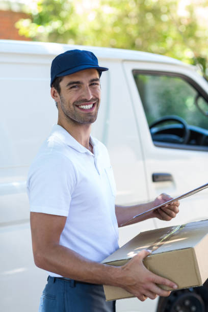 istock Cheerful delivery man carrying cardboard box 664466450