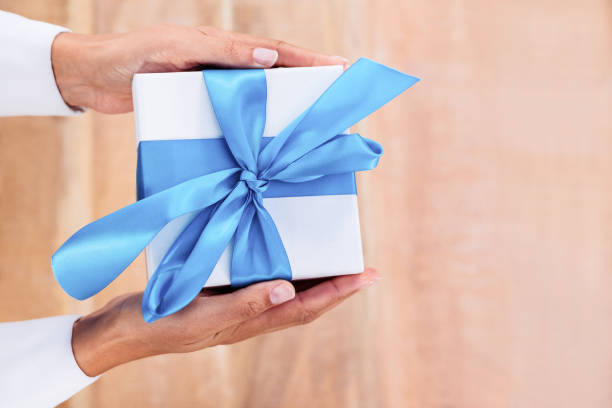 istock Woman presenting gift with blue ribbon 664467662