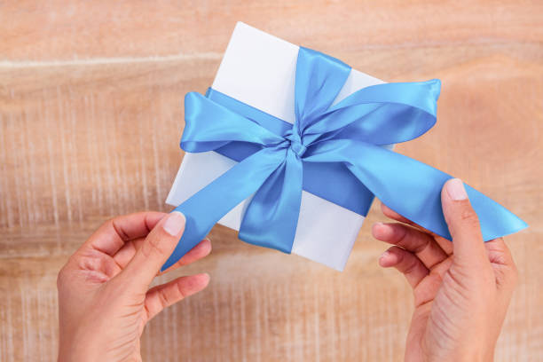 istock Woman presenting gift with blue ribbon 664470038