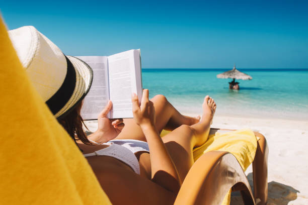 donna su lettino che legge libro sotto ombrellone sull'isola tropicale - parasol umbrella sun beach foto e immagini stock