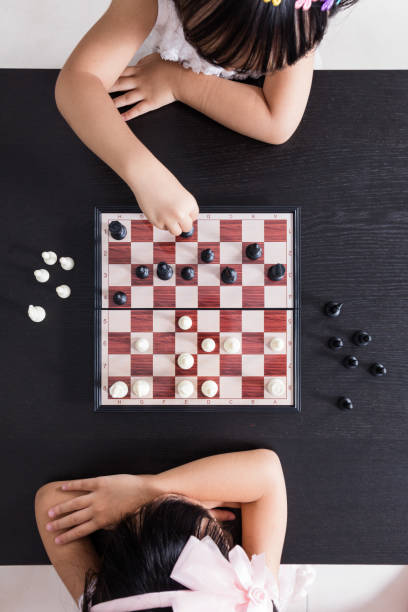veduta aerea delle sorelline cinesi asiatiche che giocano a scacchi insieme - concentration chess playing playful foto e immagini stock