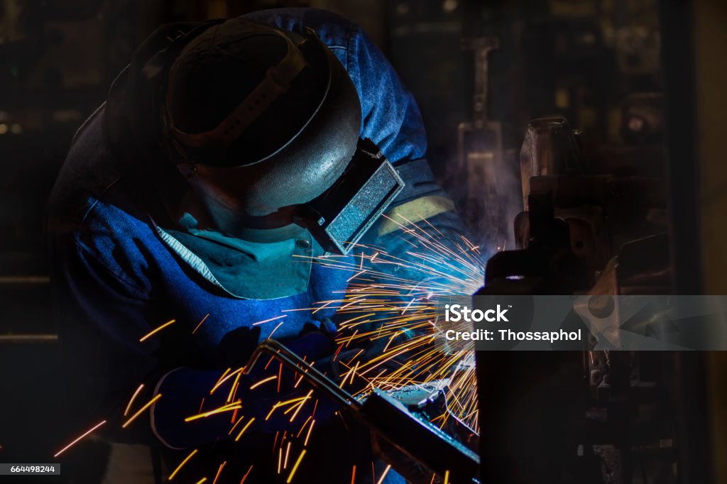 worker is welding automotive part in factory Building - Activity Stock Photo