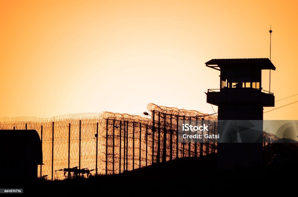 Silhouette of barbed wires and watchtower of prison. Prison Stock Photo