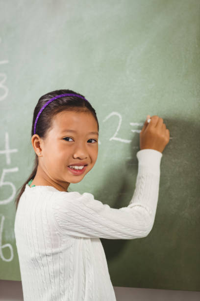 istock Girl writing with chalk on blackboard 664517860
