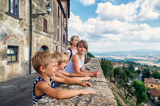Mother and kids tourists sightseeing beautiful Italian town of Volterra. Family is admiring view from terrace.

