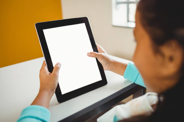 Rear view of girl using a tablet at school