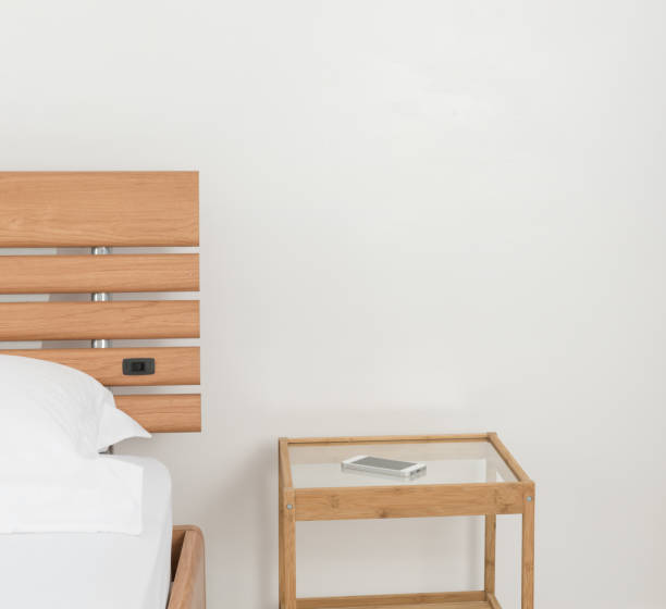 istock Mobile phone on wooden bed side table decorated in modern white bedroom 664526038