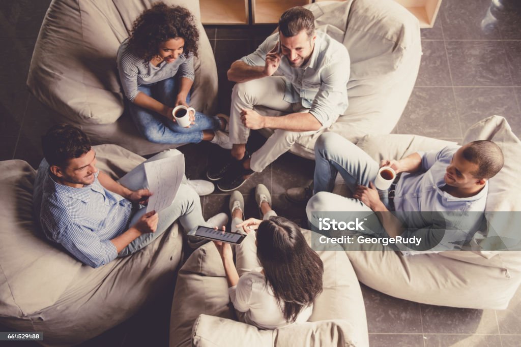 Business people working High angle view of successful young business people sharing ideas and smiling during the coffee break Coffee Break Stock Photo