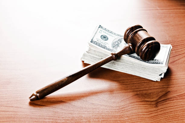 Judge's or auctioneer's wooden gavel resting on stack of banknotes