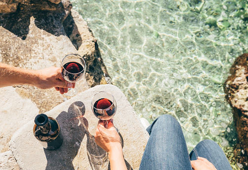 Close up image man and woman hands with goblet of wine at the sea side
