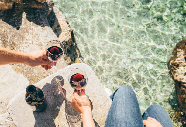 close up image man and woman hands with goblet of wine at the sea side - picnic summer break relaxation imagens e fotografias de stock
