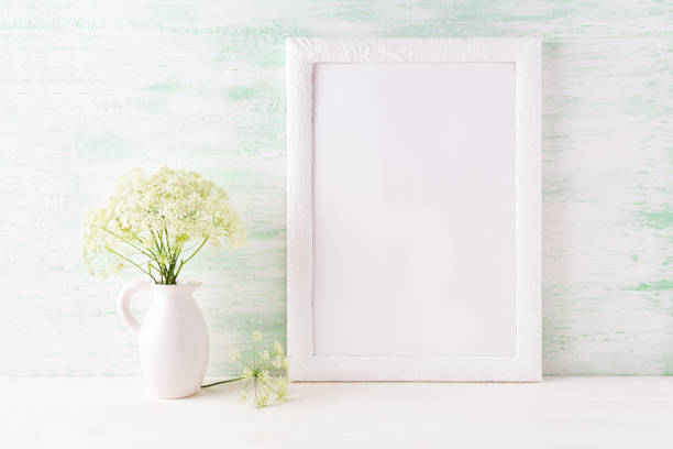 istock White frame mockup with delicate wild field flowers in pitcher 664581026