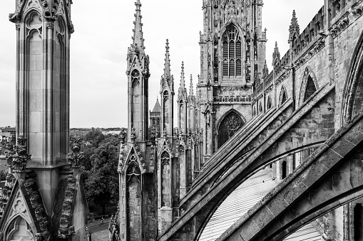 York Minster is a cathedral in York, one of the leading examples of english gothic architecture. Tower and flying buttresses on the roof of York Minster in black and white. York, North Yorkshire, United Kingdom