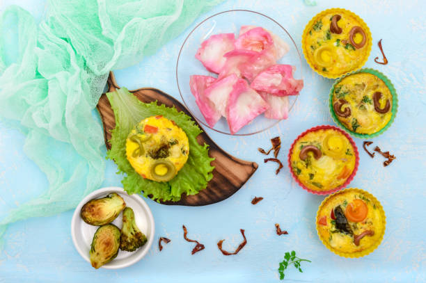 Omelette with colored pasta, mushrooms, vegetables and herbs, cooked in the form of mafins. The top view. Breakfast.