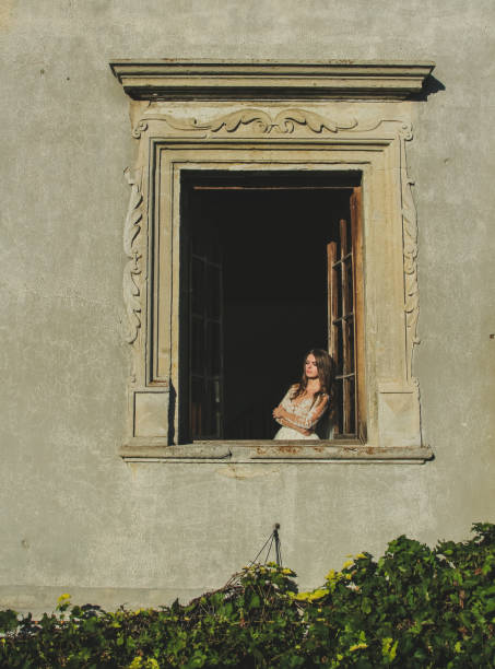 istock Sophisticated bride standing in old windows in castle 664592022