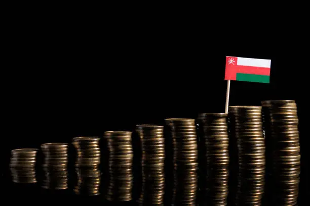 Omani flag with lot of coins isolated on black background