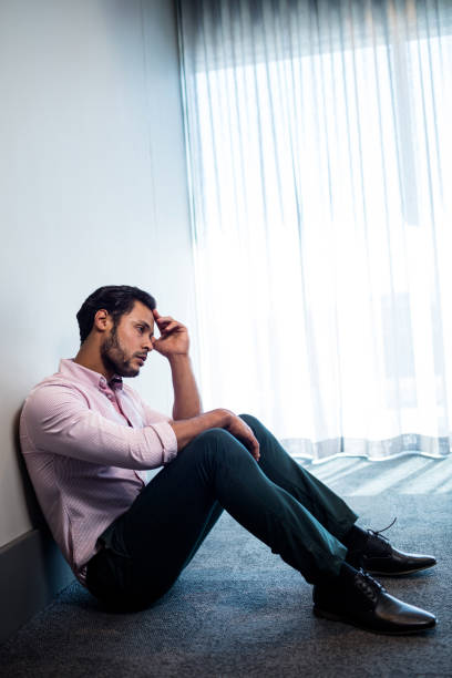 istock Upset businessman sitting against the wall 664602100
