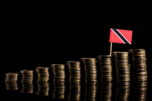 Trinidad and Tobago flag with lot of coins isolated on black background