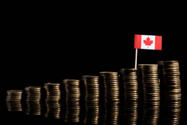 Canadian flag with lot of coins isolated on black background