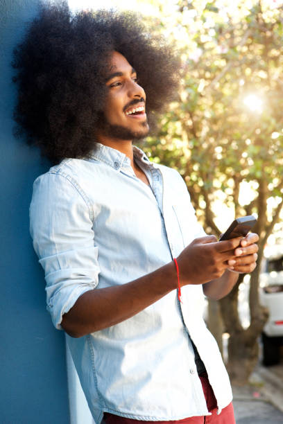 istock happy man leaning against wall with mobile phone 664603632