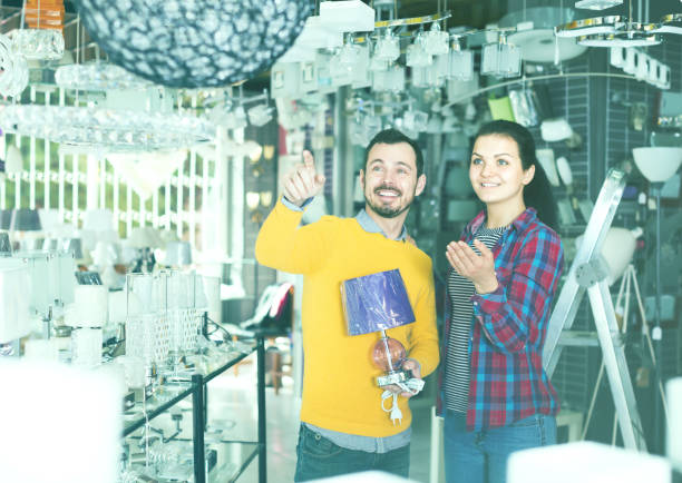 istock Smiling man points to stylish model lamp 664603804