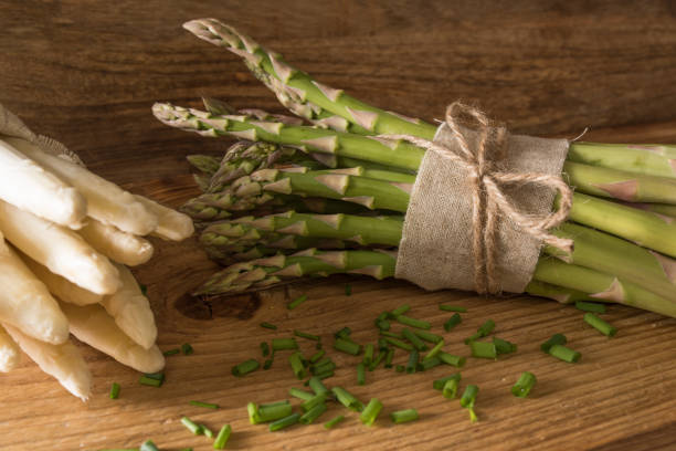 Fresh asparagus on rustic wood Bound green and white asparagus with chives on rustic wood schnittlauch stock pictures, royalty-free photos & images